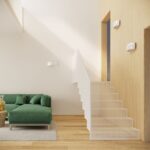White half moon wall light on a wood clad stairwell wall above a green sofa