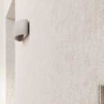 Close-up of the grey half moon wall light mounted on a textured plaster wall