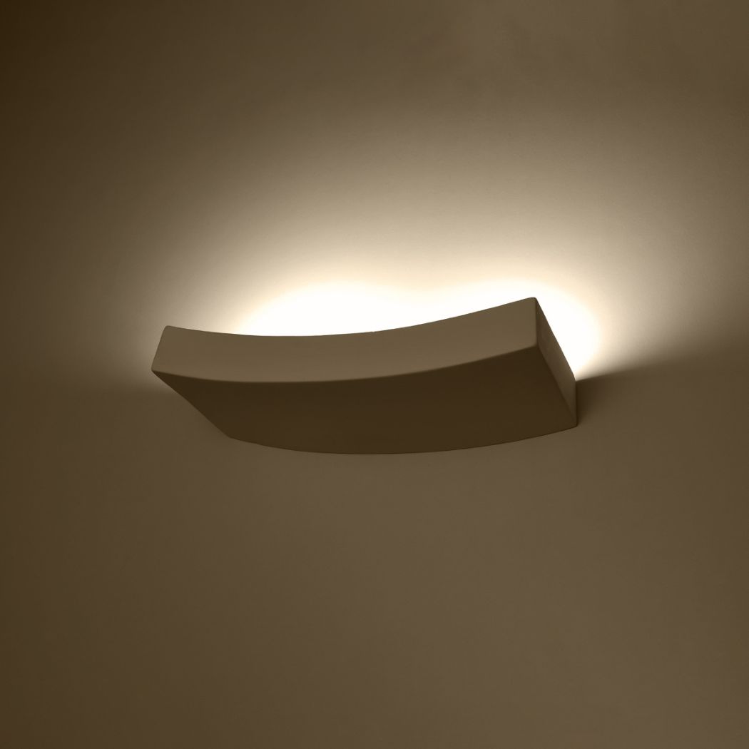 Curved white ceiling light glowing warm against a brown wall
