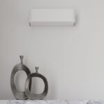 White wall light above a marble console with silver abstract sculptures