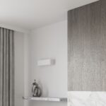 White wall light in a corner near a marble console and a curtain
