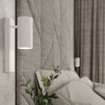 Close-up of a white cylindrical wall light on a chevron-textured headboard panel