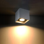 Silver ceiling spotlight mounted overhead casting a warm light beam