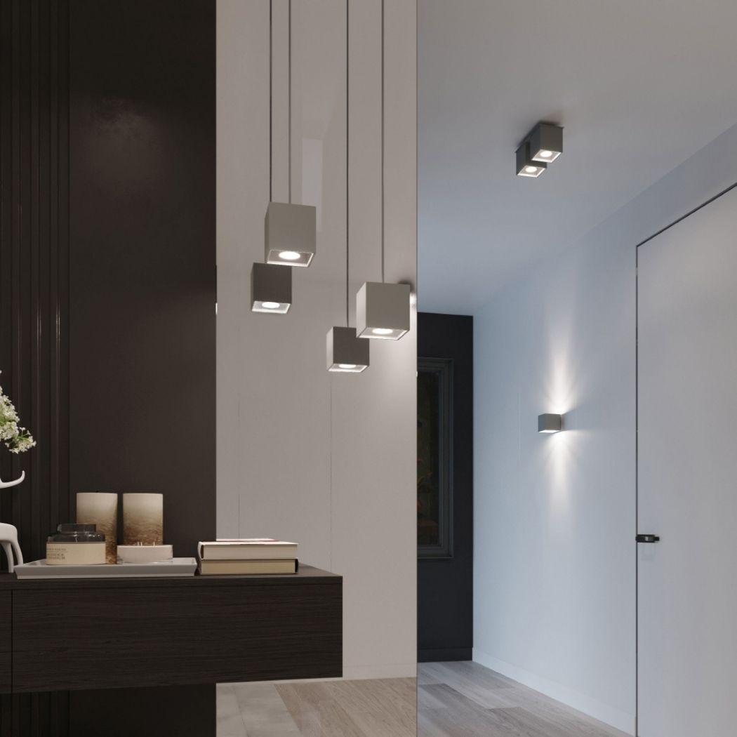 Cluster of grey cube pendants at staggered heights beside a console table and candles
