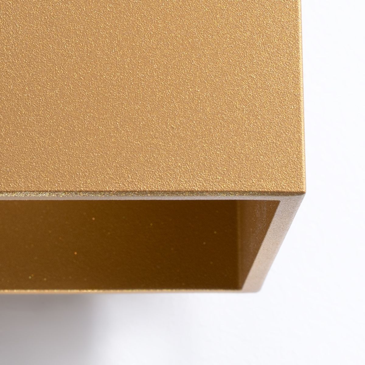 Close-up of the sharp edge and matte texture of the gold cube wall light