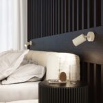 Two white ribbed spotlight wall lights above a black slatted bed headboard