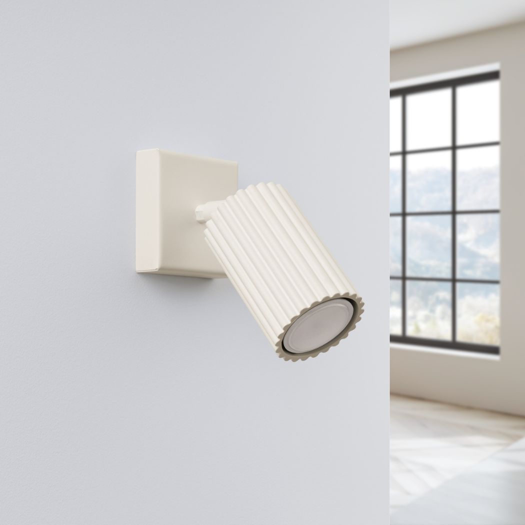 Cream ribbed adjustable spotlight wall light angled downward on a wall