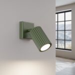 Green ribbed adjustable spotlight wall light casting a warm downward beam