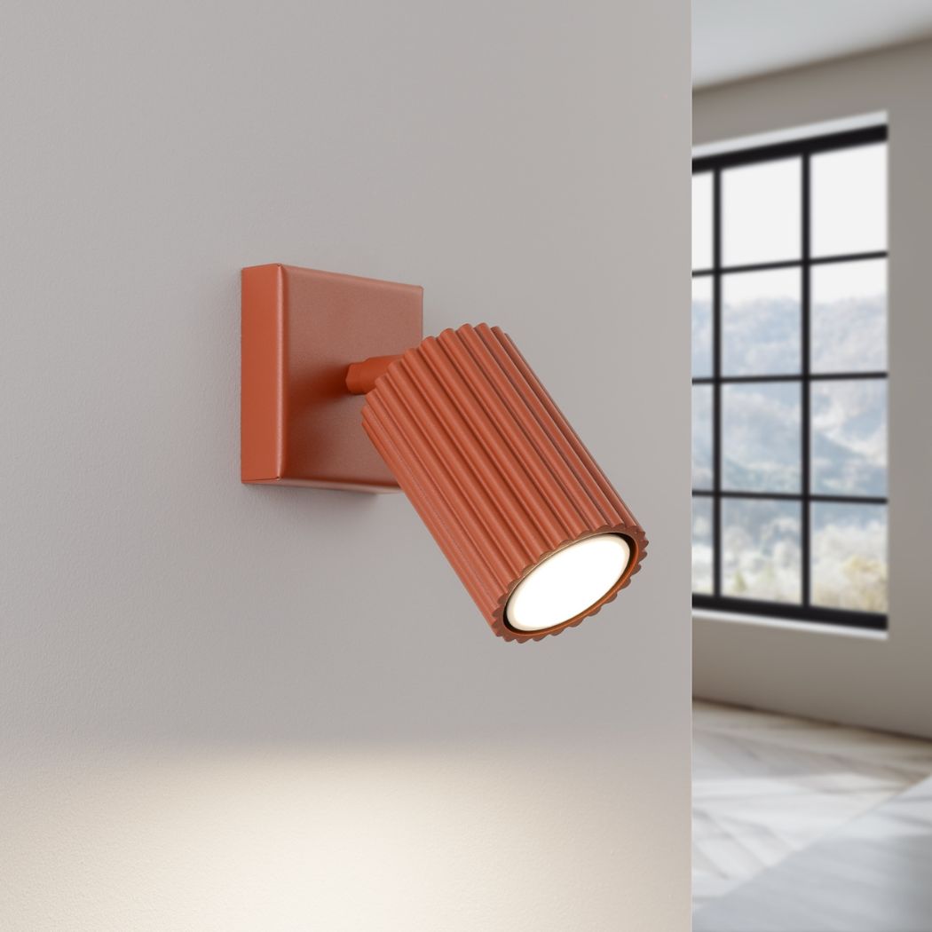 Terracotta ribbed adjustable spotlight wall light casting a warm downward beam