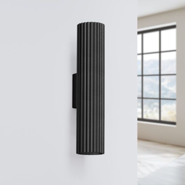 Black ribbed cylindrical wall light mounted beside a bright window