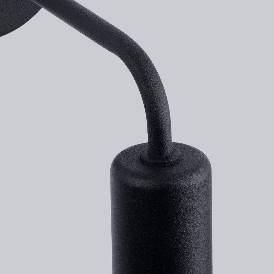 Extreme close-up of the curved black arm and bulb holder of the wall light