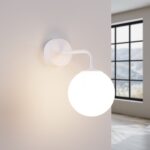 White glass globe wall light switched on near a window