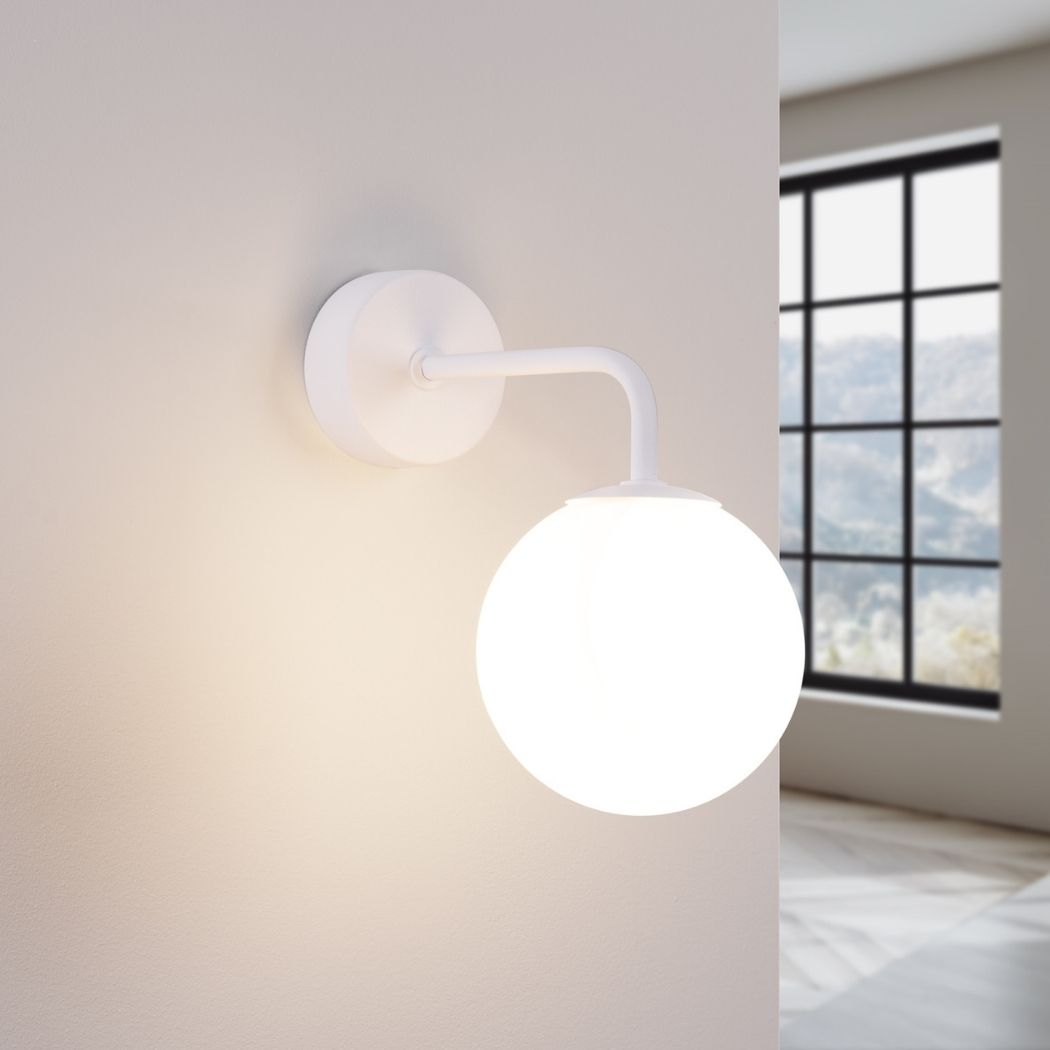 White glass globe wall light switched on near a window