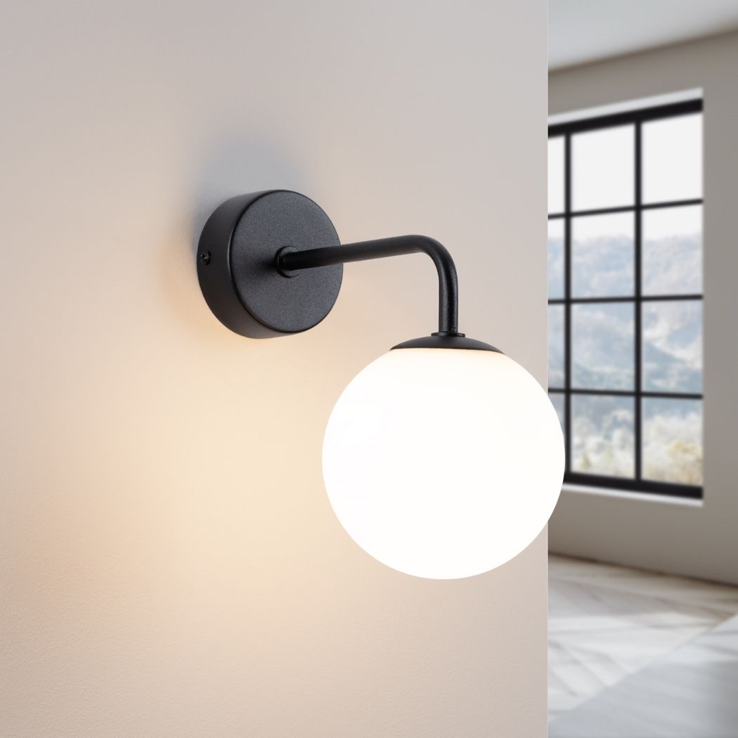 Black glass globe wall light switched on with warm light
