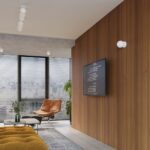 Small round glass ball wall lights on a wood slat wall in a lounge with an armchair