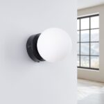 Round white glass ball wall light on a black backplate with a switch