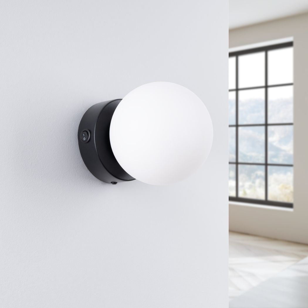 Round white glass ball wall light on a black backplate with a switch