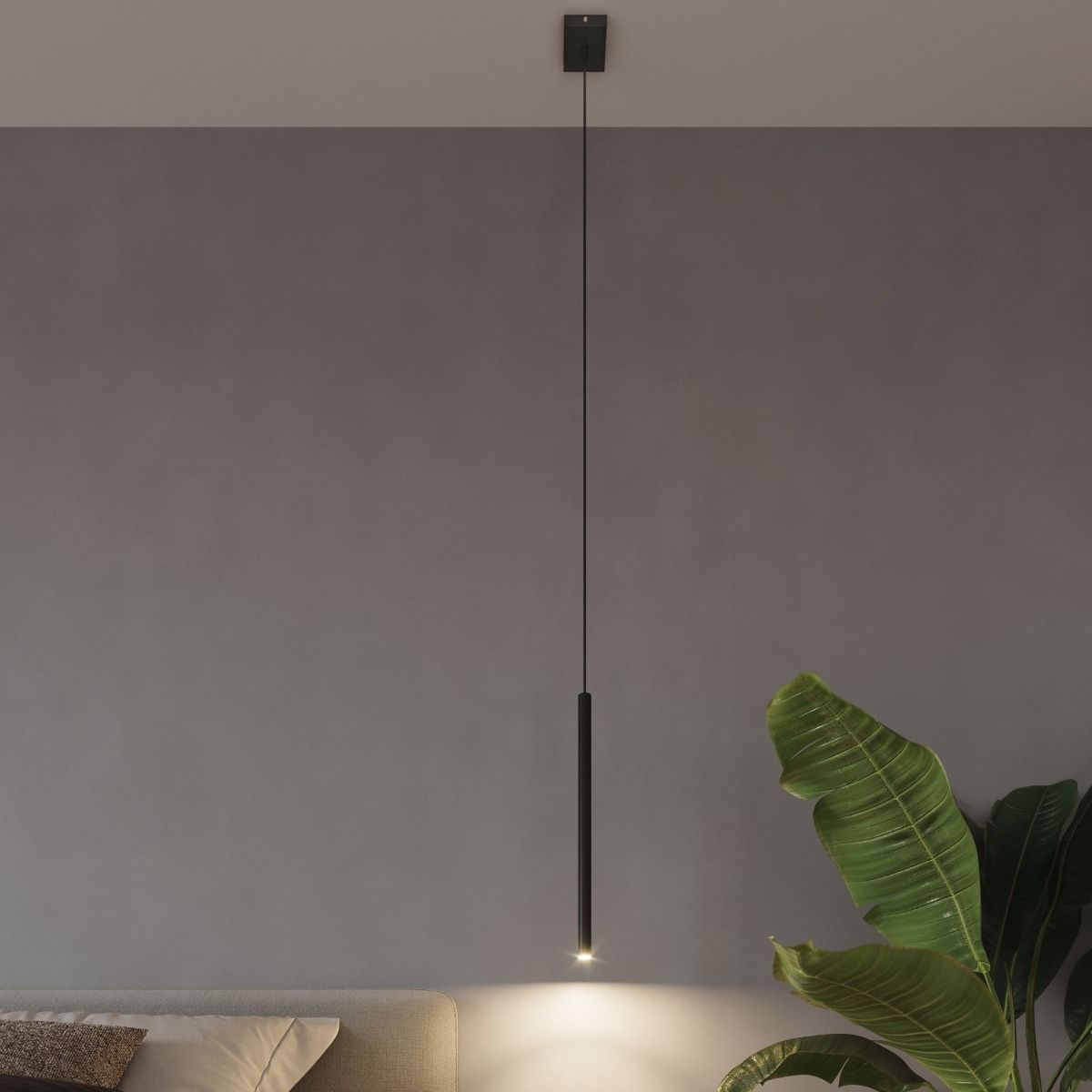 Slim black pendant light with a single narrow rod beside a plant