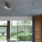 Black triple-spot ceiling light on a concrete ceiling above a kitchen island