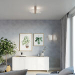 Cross shaped wood and white flush ceiling light above a white sideboard with framed botanical prints