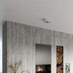 Small gray two spot ceiling light near a concrete wall and a fireplace