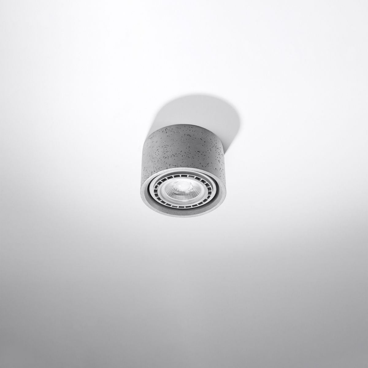 Grey concrete cylindrical adjustable ceiling spotlight angled to one side