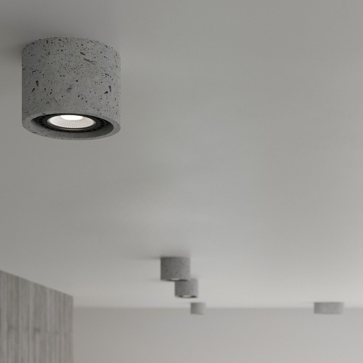 Close-up of a textured concrete ceiling spotlight in a hallway with more lights