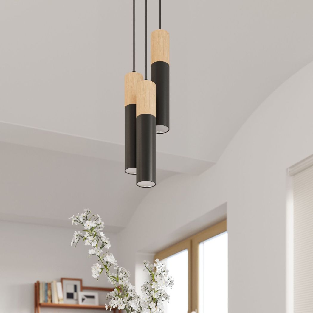 Three black and wood cylinder pendant lights hanging above white flowers
