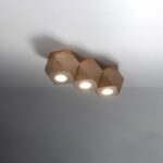Close-up of the three joined wood hexagonal spotlights with their lenses lit against the ceiling