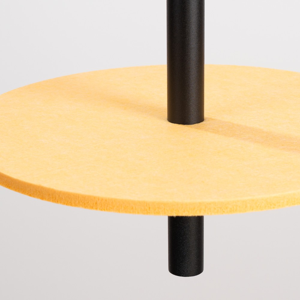 Close-up of the yellow felt disc with the black rod passing through its centre