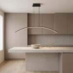 Curved black LED pendant light above a grey kitchen island with a bowl and branch