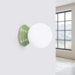 Wall light with a ribbed green ceramic base and white glass globe