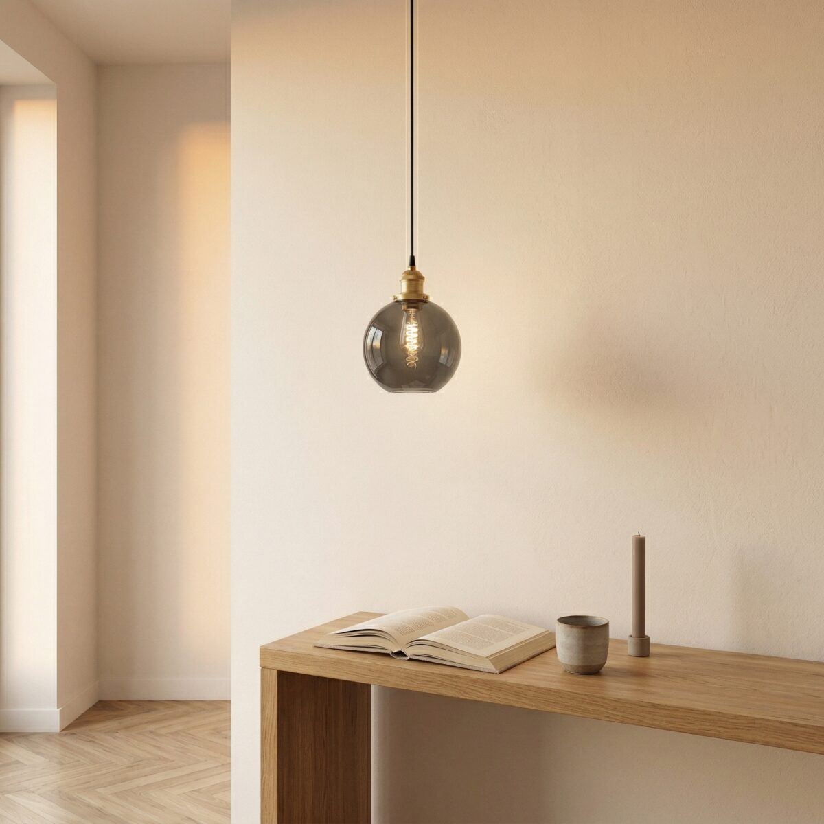 Smoked glass globe pendant light hanging above a wooden console table with a book