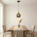 Smoked glass globe pendant light hanging above a wooden dining table with two chairs
