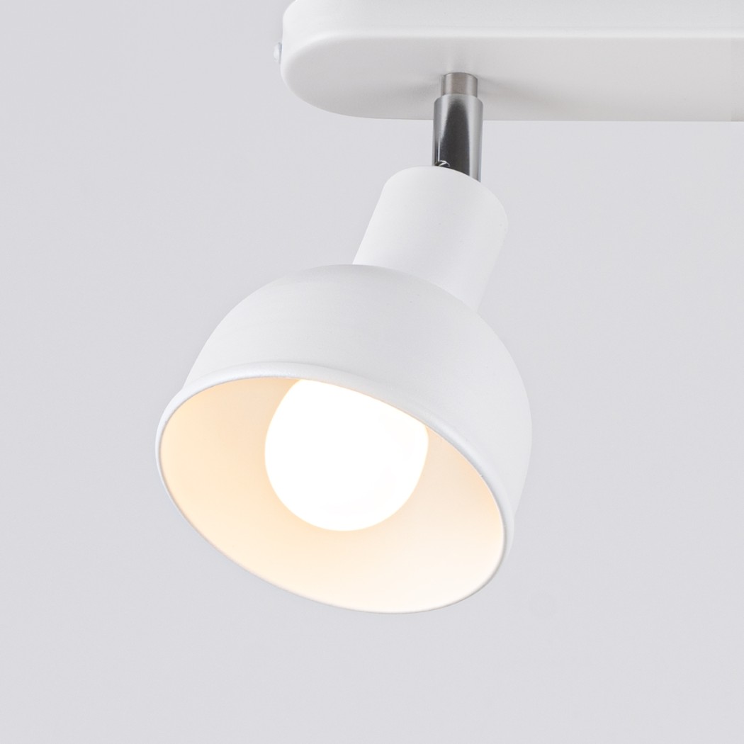 White ceiling spotlight switched on, warm bulb glowing inside the shade