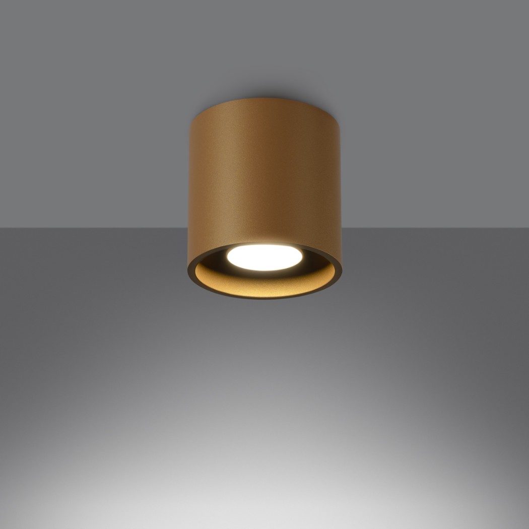 Brown cylindrical ceiling spotlight beaming light down against a grey backdrop