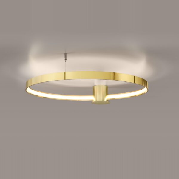 Polished gold ring pendant light glowing softly against a beige ceiling