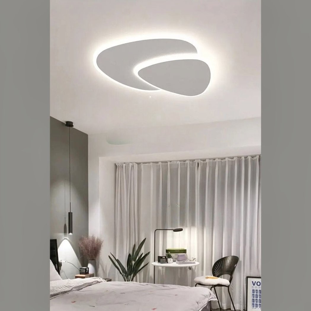 Dual-loop LED ceiling light above a bedroom with a curtained desk nook