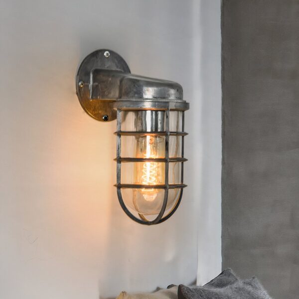 Galvanized metal industrial wall light with a caged glass shade on an angled arm