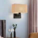 Rectangular beige fabric wall light beside a pink curtain and side table