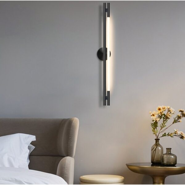 Black vertical LED wall light bar glowing beside a bed and nightstand