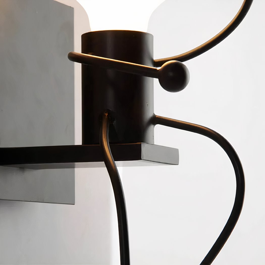 Close-up of a black wall light with curved arms holding a round diffuser