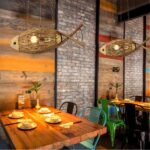 Two woven wooden fish pendant lights above a rustic restaurant dining table