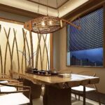 Wooden fish-shaped chandelier with exposed bulbs above a live-edge dining table