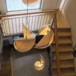 Wooden spiral pendant lights with ribbed shell-like shades glowing over a staircase