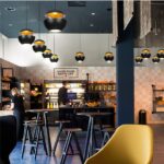 Row of black and gold-lined dome pendants above a cafe counter