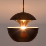 Black dome pendant light with a flared brass inner cone glowing warmly