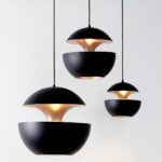 Three black open sphere pendants with gold interiors shown off on a white background