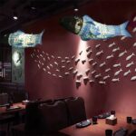 Fish-shaped lantern pendant lights hanging above a restaurant table