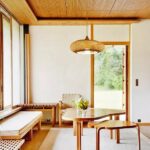 Woven bamboo drum pendant glowing above a wooden dining table